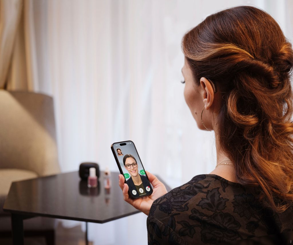 Woman using a smartphone with Oticon Real hearing aids