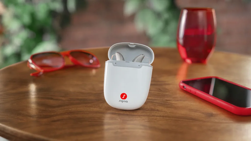 Signia hearing aids in a portable charger on a table